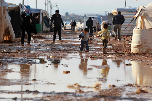 Young Syrian refugees stand outside their tents after heavy rain Jan. 10 at the Zaatari refugee camp in the Jordanian border town of Mafraq. Snow, driving rain and howling winds in early January compounded the already desperate situation for Syrians caug ht up in 22 months of civil war seeking to oust President Bashar Assad. (CNS photo/Muhammad Hamed, Reuters)