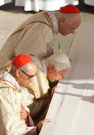 Pope Benedict XVI kisses the altar as he arrives to celebrate the canonization Mass for seven new saints in St. Peter's Square at the Vatican Oct. 21. Also pictured are Cardinals Santos Abril Castello, archpriest of the Basilica of St. Mary Major, and Ed win F. O'Brien, grand master of the Equestrian Order of the Holy Sepulcher. Among those canonized were two North Americans -- St. Kateri Tekakwitha, an American Indian born in upstate New York who died in Canada in 1680, and St. Marianne Cope, who worked with leprosy patients on the Hawaiian island of Molokai. (CNS photo/Paul Haring)