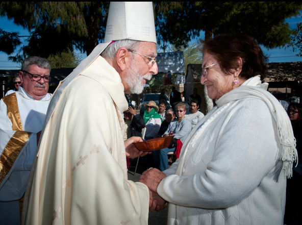 Teresa Sandoval delivers the Communion hosts to Bishop Gerald F. Kicanas of Tucson, Ariz., during an outdoor Mass Dec. 1 in San Luis, Ariz., just north of the U.S.-Mexico border. The Mass honored the hard work of migrant workers essential for harvesting crops in the area. (CNS photo/Rick D'Elia, Catholic Relief Services)