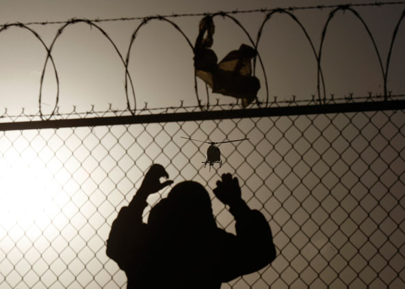 A man watches a U.S. Border Patrol helicopter March 8 from a fence at the U.S.-Mexico border in Ciudad Juarez, Mexico. While politicians and advocacy organizations work at coming up with legislation to reform the U.S. immigration system, the Jesuits are tackling some of its problems head on at the border, in higher education institutions and in parishes. (CNS photo/Jose Luis Gonzalez, Reuters)