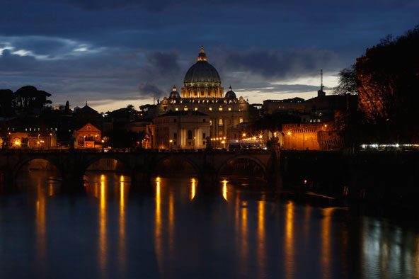 The Vatican's St. Peter's Basilica is illuminated while seen from the Tiber River in Rome March 11, the evening before the world's cardinals gather for the conclave in the Sistine Chapel to elect a new pope. (CNS photo/Paul Hanna, Reuters)