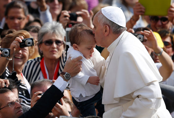 Pope Francis kisses a young child as he arrives for his general audience in St. Peter's Square at the Vatican April 17. (CNS photo/Paul Haring)