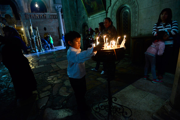 A boy lights candles during the Easter Vigil in the Church of the Holy Sepulcher in Jerusalem's Old City March 30. (CNS photo/Debbie Hill)