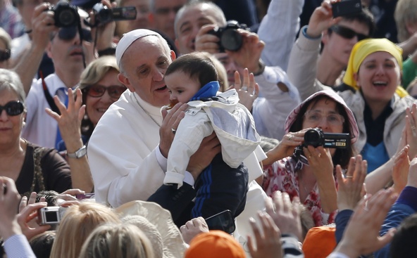 Pope Francis greets a baby as he arrives to lead his general audience in St. Peter's Square at the Vatican April 17. (CNS photo/Paul Haring)