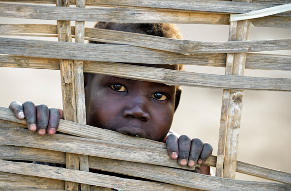 A boy displaced by violence in Sudan peers through a fence in Agok, a town in the contested southern Abyei region, in February. Tens of thousands of people fled to Agok in 2011 after an attack by soldiers and militias from the northern part of Sudan. The re are 28.8 million internally displaced persons in the world, according to the Pontifical Council for Migrants and Travelers. (CNS photo/Paul Jeffrey)