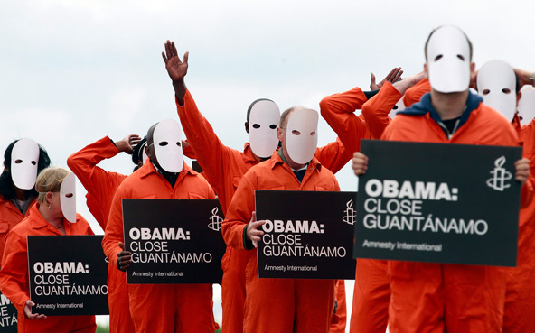 Masked activists from Amnesty International dressed as Guantanamo Bay detainees protest the military-run prison June 16 outside Waterfront Hall in Belfast, Northern Ireland, prior to the Group of Eight summit, which President Barack Obama attended. As a hunger strike at the U.S.-run prison continued, a growing chorus of voices, including international human rights groups and at least one U.S. Catholic bishop, called for Obama to review conditions at the facility and make good on his pledge to close it. (CNS photo/Cathal McNaughton, Reuters)