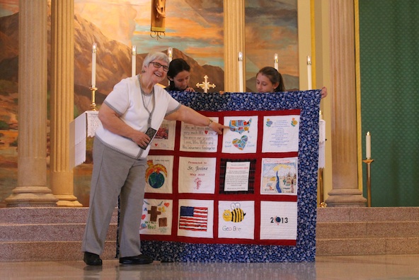 Benedictine Sister Josine points out some of the symbolism and craftsmanship that  went into creating a quilt as part of her retirement gift. St. Thomas the Apostle students and staff presented it on the final day of school June 7. (Ambria Hammel/CATHOLIC SUN)