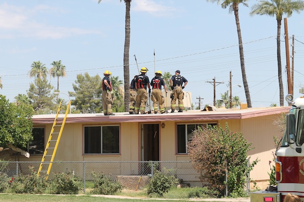 Phoenix firefighters cut holes in the roof during a mock fire demonstration at St. Theresa School June 7. The activity kicked off a phased demolition and rebuilding of the Early Education Center. The powerful fire hoses also provided students with heat relief on the last day of school. (Ambria Hammel/CATHOLIC SUN)