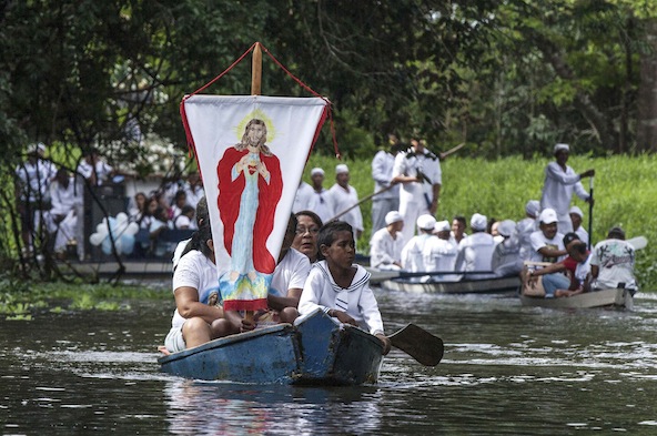 Pilgrims display banner with image of Christ during 2012 river procession in Brazil