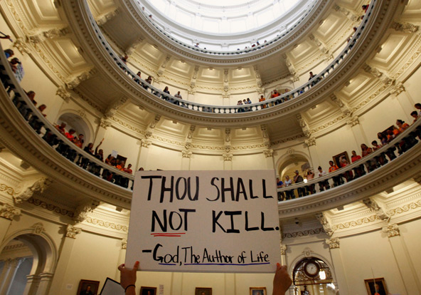 A pro-life supporter holds a placard as protesters line the railing on the second floor of the rotunda of the State Capitol in Austin, Texas, July 12 as the state Senate considers a bill to restrict abortion. The Republican-led Senate the measure to adop t tougher abortion regulations July 13. (CNS photo/Mike Stone, Reuters)