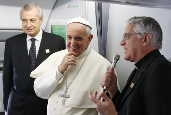 Pope Francis smiles as Jesuit Father Federico Lombardi, the Vatican spokesman, addresses journalists aboard the papal flight to Brazil July 22. The pope is making his first international trip to attend World Youth Day. (CNS photo/Paul Haring)