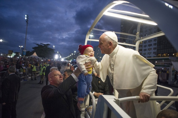 Pope Francis kisses a baby while riding in the popemobile along Copacabana beach on his way to the Way of the Cross during World Youth Day in Rio de Janeiro July 26. (CNS photo/L'Osservatore Romano)
