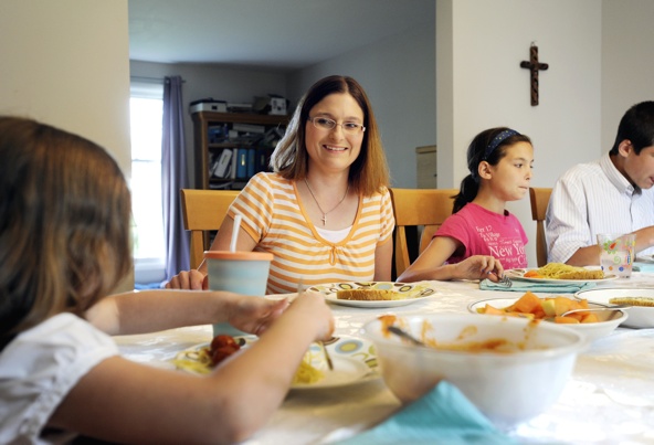 "The first setting in which faith enlightens the human city is the family," says the encyclical "Lumen Fidei" ("The Light of Faith") from Pope Francis. Pictured is Jennifer Lozy-Lester at dinner with her family in Greece, N.Y. (CNS file photo/Mike Crupi, Catholic Courier)