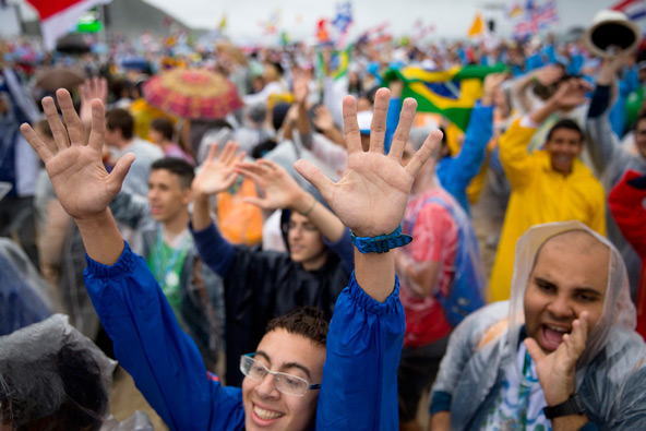 Pilgrims wave to television cameras during the opening Mass of World Youth Day in Rio de Janeiro July 23. Young Latin Americans say they are more excited to take their faith to the street after the weeklong celebration. (CNS photo/Tyler Orsburn)