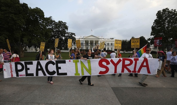 Protesters carry a banner during a rally outside the White House in Washington Aug. 29. As speculation mounted about Western air strikes on Syria, a U.S. bishops' committee called for a political solution, and Catholic leaders in Europe warned military intervention could lead to an escalation of hostilities. (CNS photo/Jason Reed) 