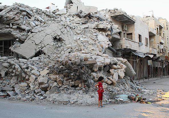 In this Sept. 8 photo, a girl stands in front of a building destroyed by what activists said was shelling by forces loyal to Syrian President Bashar Assad in the northern town of Ariha. (CNS photo/Houssam Abo Dabak, Reuters)