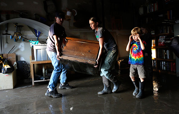 Chris and Shanda Roberson in Longmont, Colo., carry a flood-soaked antique trunk from their garage Sept. 16 as their son, Rowen, looks on. An eighth person in Colorado has died and more than 600 people are unaccounted for in the ferocious flooding and re lentless rain ravaging communities across the state, according to officials. (CNS photo/Rick Wilking, Reuters)