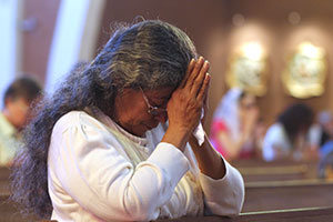 A woman kneels in prayer at Ss. Simon and Jude Cathedral Sept. 7 where a five-hour vigil was being held in response to Pope Francis’ call for fasting and prayer on behalf of peace in Syria. (J.D. Long-Garcia/CATHOLIC SUN)