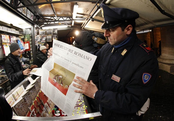 A policeman holds a copy of L'Osservatore Romano newspaper in Rome Feb. 11. The most widely used communication tool in Catholic Church is the parish bulletin, followed by a diocesan newspaper or magazine -- in print form -- which one in four adult Catholics have read in the past three months, CARA reports. (CNS photo/Giampiero Sposito, Reuters)