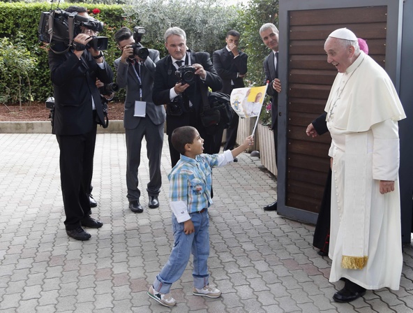 A child waves a flag as Pope Francis arrives at the Caritas residence in the Italian pilgrimage town of Assisi Oct. 4. The pontiff was making his first pilgrimage as pope to the birthplace of his papal namesake. (CNS photo/Stefano Rellandini, Reuters)