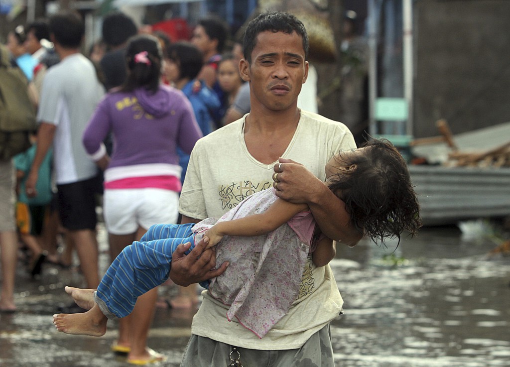 A father carries the lifeless body of his daughter Nov. 10 on the way to the morgue after Super Typhoon Haiyan hit Tacloban, Philippines. The typhoon, one of the strongest storms in history, is believed to have killed tens of thousands, but aid workers w ere still trying to reach remote areas. (CNS photo/Nino Jesus Orbeta, Philippine Daily Inquirer via Reuters)