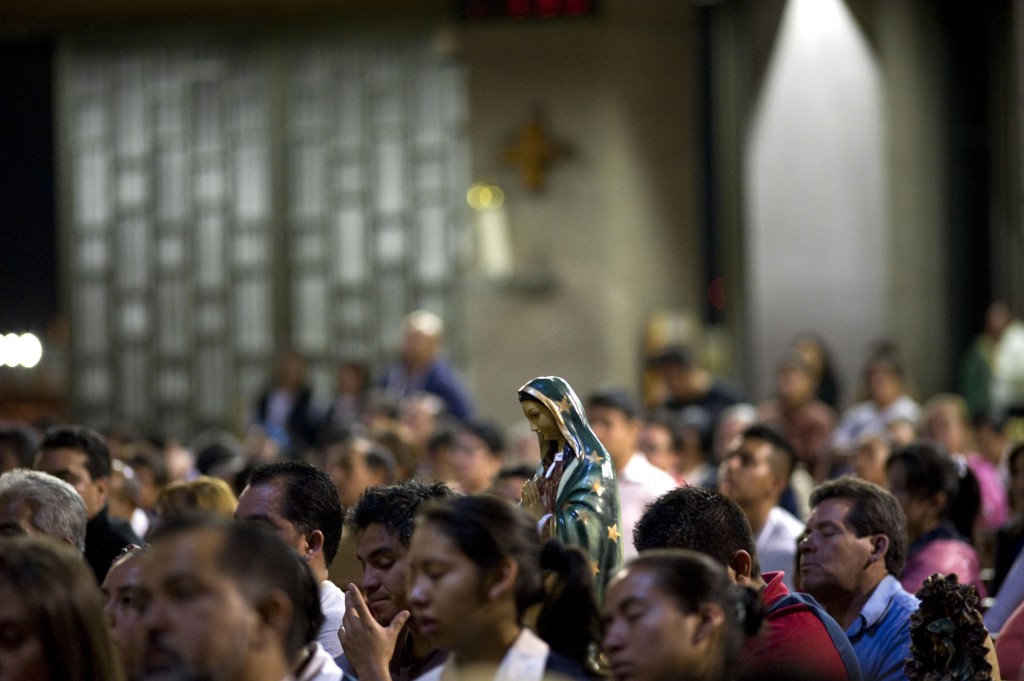 A statue of Our Lady of Guadalupe is seen in a crowd attending Mass during the first day of a meeting of church leaders at the Basilica of Our Lady of Guadalupe in Mexico City Nov. 16. Bishops and church leaders from the Americas gathered Nov. 16-19 at the basilica to discuss the new evangelization in the Americas. (CNS photo/David Maung)