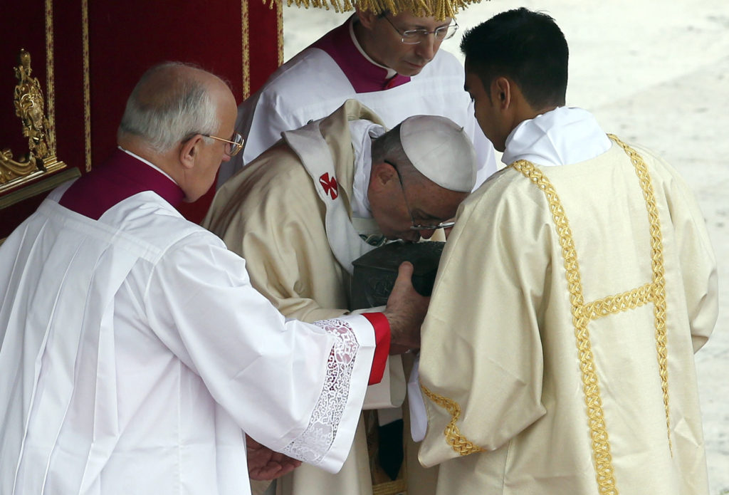 Pope Francis venerates the relics of St. Peter the Apostle on the altar during a Mass in St. Peter's Square at the Vatican Nov. 24. The bone fragments, which were discovered during excavations of the necropolis under St. Peter's Basilica in the 1940s, are kept in the pope's private chapel but had never been displayed in public. (CNS photo/Stefano Rellandini, Reuters)