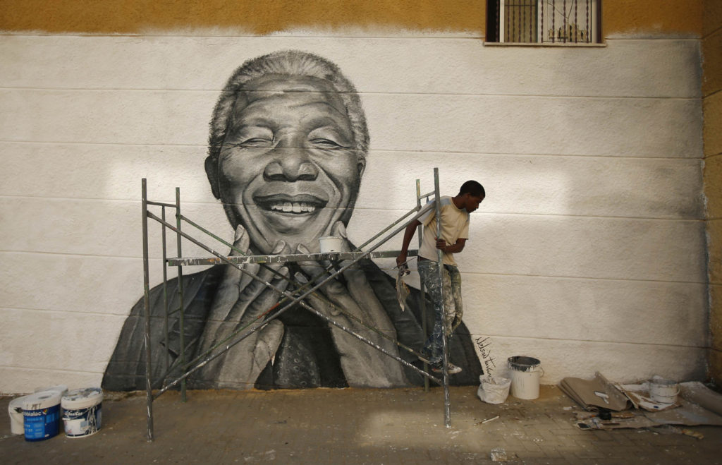 A man works on a graffiti image of Nelson Mandela which he painted during festivities in his neighborhood in late June in Lisbon, Portugal. The ailing former South African president is not doing well but is continuing to put up a courageous fight from hi s deathbed, according to his family. (CNS photo/Rafael Marchante, Reuters)