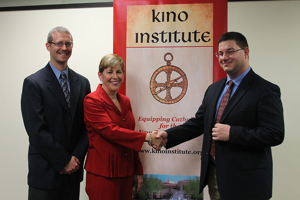 MaryBeth Mueller and Steve Greene with the diocesan Office of Evangelization symbolically welcome Dr. Leroy Huizenga, from the University of Mary after finalizing a credit agreement between the diocesan Kino Institute and U-Mary. (Ambria Hammel/CATHOLIC SUN)