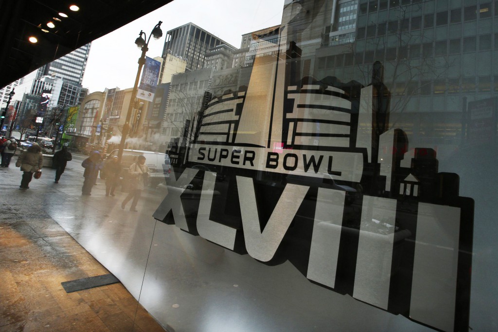 Pedestrians are reflected on windows displaying the Super Bowl icon Jan. 27 as preparations continued for Super Bowl XLVIII in New York. Margot Morris, program director for the Tri-State Coalition for Responsible Investment, says a lot of "positive feedback" has been reported from hotels expecting an influx of visitors for the Feb. 2 Super Bowl  regarding efforts to curb human trafficking, primarily sex trafficking, surrounding the event. (CNS photo/Eduardo Munoz, Reuters)