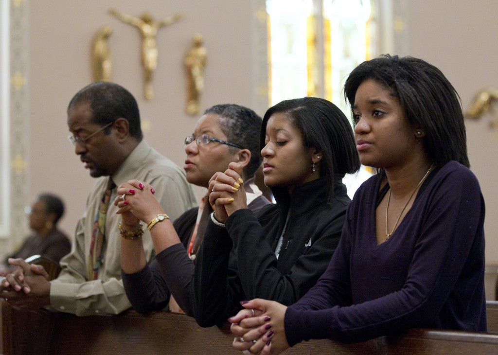 The Brooks family — Joe, Desiree, Gabrielle and Alyssa — pray after arriving for Sunday Mass at St. Joseph's Catholic Church in Alexandria, Va., in this 2011 file photo. According to the first study of its kind, Black Catholics in the U.S. are highly engaged with their religion and parish life, more so than white Catholics. (CNS photo/Nancy Phelan Wiechec)