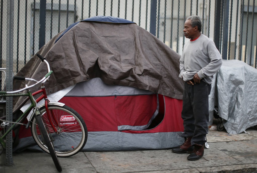 A man stands outside his tent in 2013 on Skid Row in downtown Los Angeles. The 50th anniversary of President Lyndon Johnson's declaration of the War on Poverty Jan. 8 prompted a renewed commitment by Catholic and other faith groups to address poverty. (CNS photo/Lucy Nicholson, Reuters)