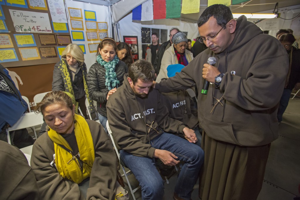 Franciscan Brother Juan Turios of  Action Network prays Nov. 30 with immigration reform advocates taking part in "Fast for Families" in a tent on the National Mall near the U.S. Capitol in Washington. The fast is aimed at pressuring the U.S. House of Representatives to vote on comprehensive immigration reform legislation. (CNS photo/Jim West) 