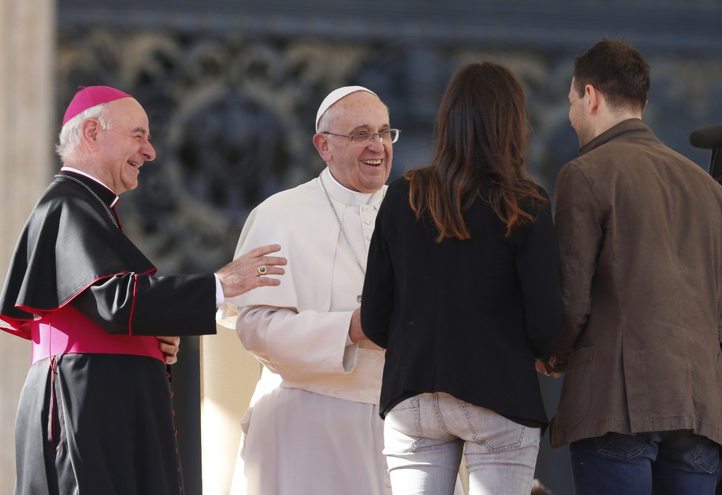 Pope Francis greets Miriam and Marco, an engaged couple who spoke during an audience for engaged couples in St. Peter's Square at the Vatican Feb. 14, Valentine's Day. At left is Archbishop Vincenzo Paglia, president of the Pontifical Council for the Family. (CNS photo/Paul Haring)