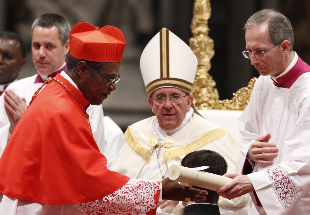 Cardinal Kelvin Felix, retired archbishop of Castries, St. Lucia, accepts his scroll from Msgr. Guido Marini after receiving the red biretta from Pope Francis during a consistory in St. Peter's Basilica at the Vatican Feb. 22. Pope Francis created 19 new cardinals in the presence of Pope Benedict XVI, who made his first public appearance at a liturgy since his retirement. (CNS photo/Paul Haring) 