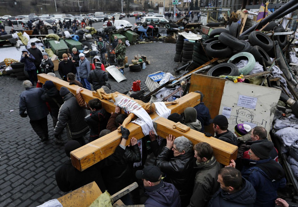 Mourners carry a large wooden crucifix past a barricade during a memorial procession in Independence Square in Kiev, Ukraine, Feb. 25. Dozens of protesters have been killed since November. (CNS photo/Yannis Behrakisi, Reuters)