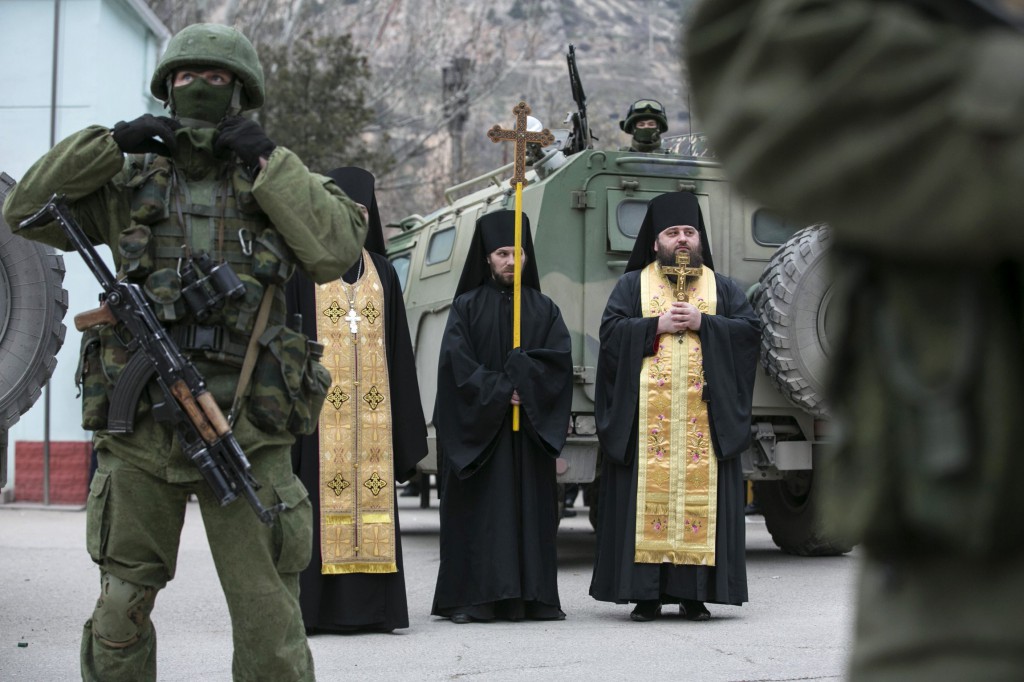 Orthodox clergymen pray next to armed servicemen near Russian army vehicles outside a Ukrainian border guard post in Ukraine's Crimean region March 1. Catholic leaders in Crimea say Ukraine has the right to determine its own future, and they urge prayers for peace. (CNS photo/Baz Ratner, Reuters) 