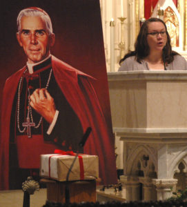 With evidence of her son's alleged miraculous healing boxed and sealed in front of a portrait of Archbishop Fulton J. Sheen, Bonnie Engstrom gives a reading at a 2011 Mass at St. Mary's Cathedral in Peoria, Ill. Bishop Daniel R. Jenky of Peoria, president of the Archbishop Fulton Sheen Foundation ,said early March 6 he received word that the seven-member board of medical experts who advise the Vatican Congregation for Saints' Causes has unanimously approved a miracle attributed to the intercession of Archbishop Sheen. (CNS photo/Tom Dermody)  
