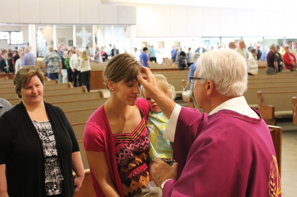 A young mother and her daughters were on hand at Corpus Christi Parish March 5 to receive blessed ashes. 