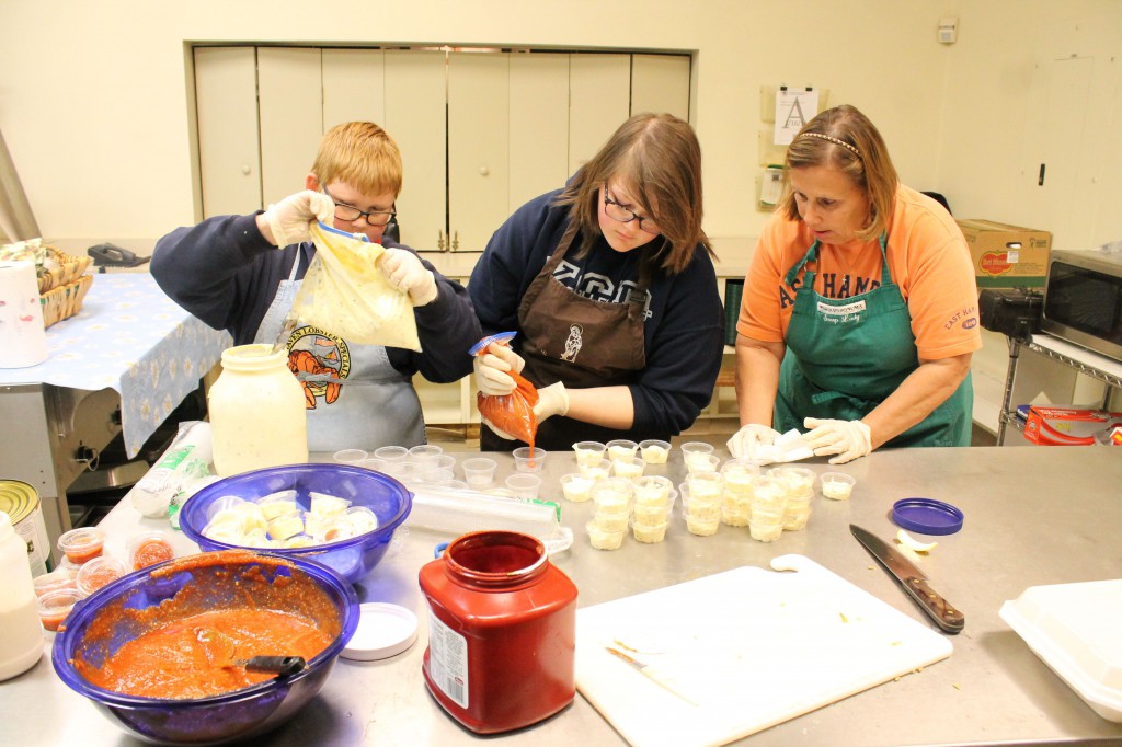 Cindi Banker and her grandchildren, Sarah Goins, 14, and Matthew Goins, 10, mix up the tartar and cocktail sauce for the St. Theresa Parish Lenten fish fry March 11. (Joyce Coronel/CATHOLIC SUN)