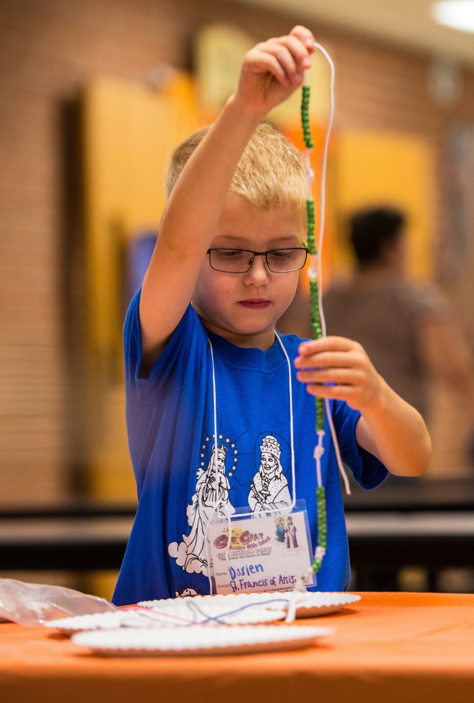 Darien Arndorfer, 6, uses beads and string to create a rosary during Vacation Bible School in this 2013 file photo at St. Bernard School in Green Bay, Wis. (CNS photo/Sam Lucero, The Compass)