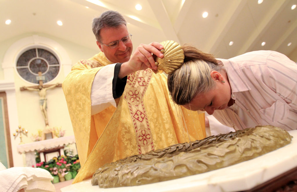 Father Gregory Yacyshyn baptizes catechumen Susan Zabiela at the Easter Vigil at St. Jude Church in Mastic Beach, N.Y., April 7. During the vigil four catechumens received the sacraments of initiation -- baptism, confirmation and first Communion -- and eight candidates were confirmed and received their first Communion. (CNS photo/Gregory A. Shemitz, Long Island Catholic)  