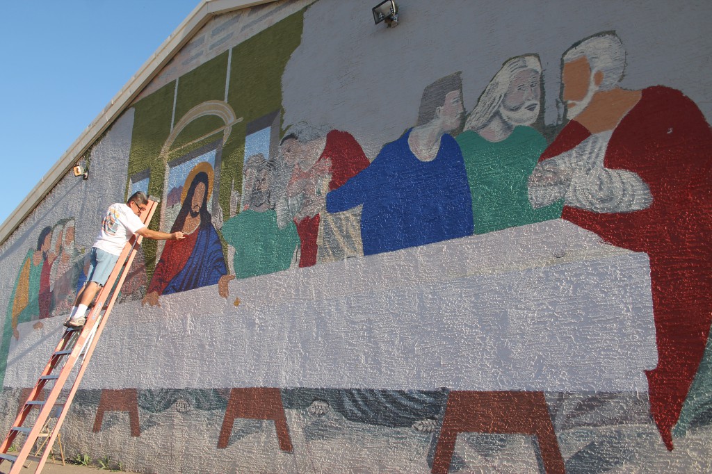David Murrieta restores his "Last Supper" mural outside of Blessed Sacrament Parish in Tolleson April 15 (Ambria Hammel/CATHOLIC SUN)