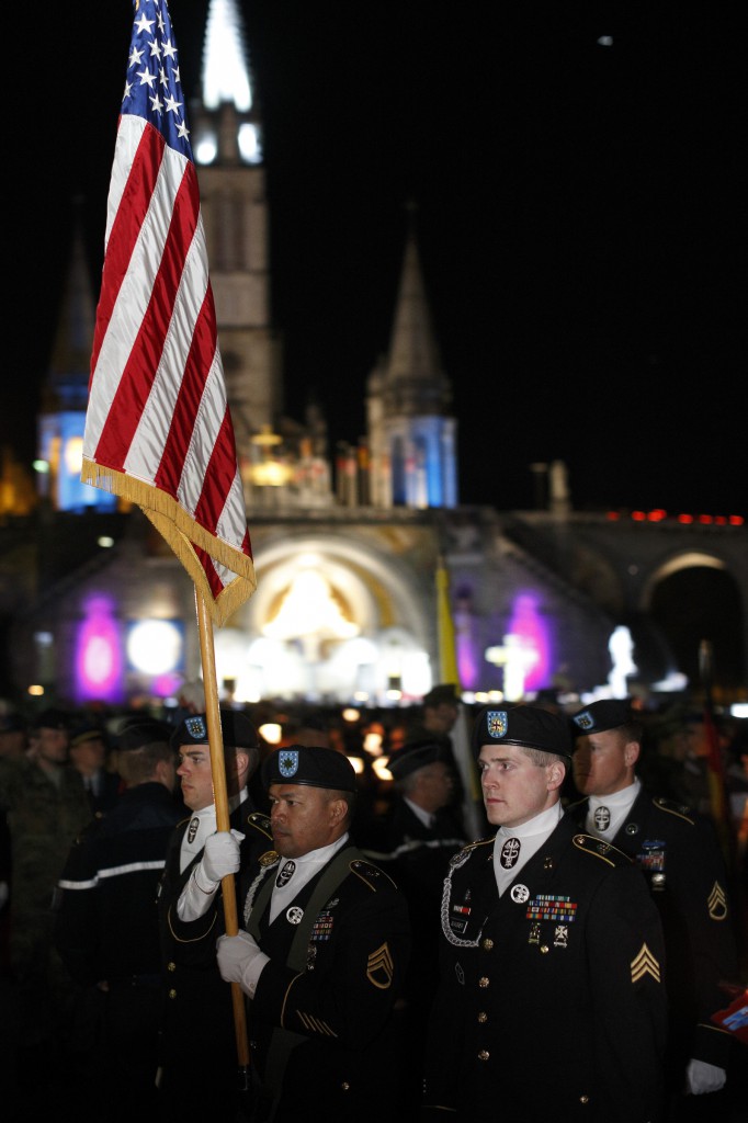 The U.S. flag is carried in procession as military personnel leave after a candlelight vigil at the Shrine of Our Lady of Lourdes in southwestern France May 17. About 60 wounded U.S. military personnel, together with family members and caregivers, were a part of the annual International Military Pilgrimage to Lourdes. (CNS photo/Paul Haring)  