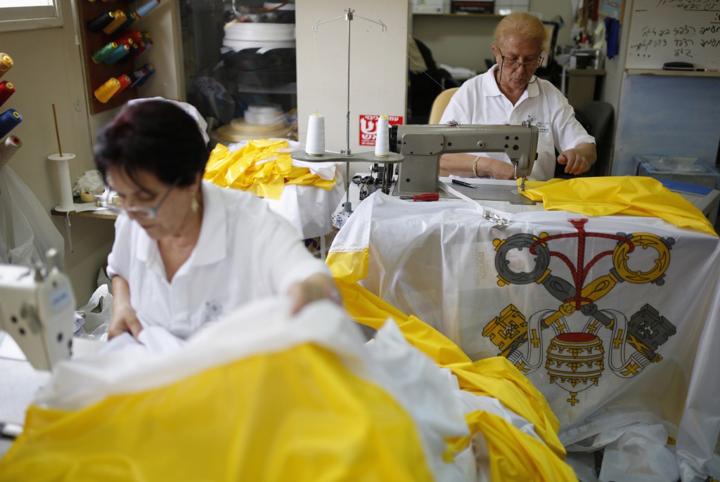 Women in Israel sew Vatican flags May 21 at the Marom factory in Kfar Sava near Tel Aviv, ahead of the May 24-26 papal visit. Pope Francis will make his first trip to the region, visiting Jordan, the Palestinian territories and Israel. (CNS photo/Amir Cohen, Reuters)  