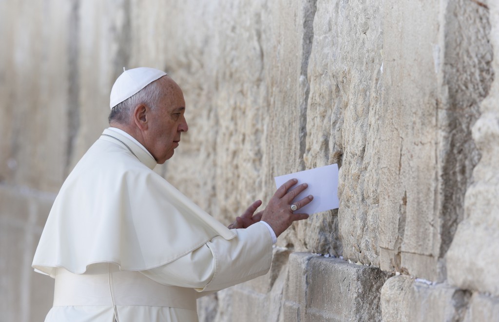 Pope Francis places a note in the Western Wall in Jerusalem May 26. The pope stood for more than a minute and a half with his right hand against the wall, most of the time in silent prayer, before reciting the Our Father. Then he followed custom by leaving a written message inside a crack between two blocks.(CNS photo/Paul Haring)