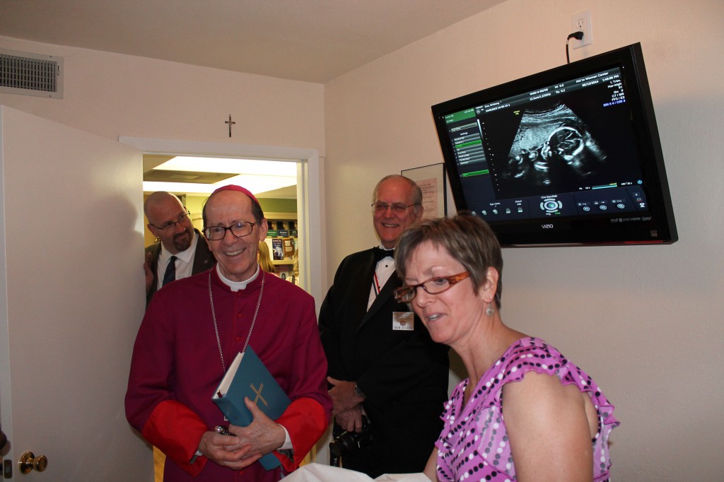 Kelly Sarotte, executive director of the Aid to Women Center, uses the new ultrasound machine donated by the Knights of Columbus as Bishop Thomas J. Olmsted looks on. (Joyce Coronel/CATHOLIC SUN)
