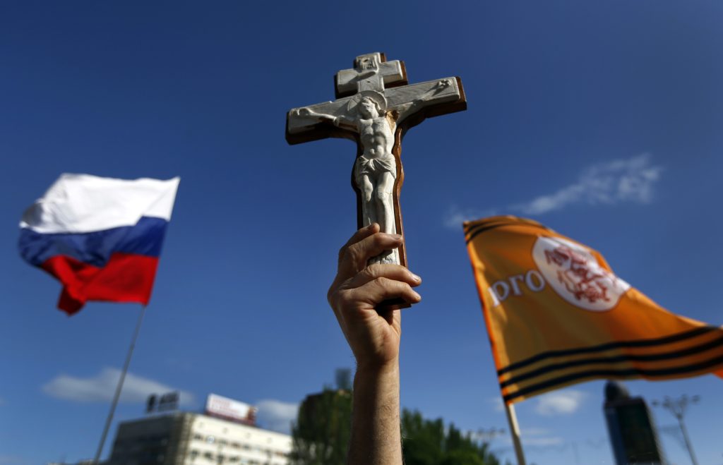A pro-Russian man holds a crucifix next to a Russian flag during a demonstration in Donetsk's Lenin Square May 24 against the Ukrainian elections. Pro-Russian insurgents have prevented at least half of the election districts in the embattled east of the country to prepare for the May 25 presidential election, a Ukrainian official says. (CNS photo/Yannis Behrakis, Reuters)