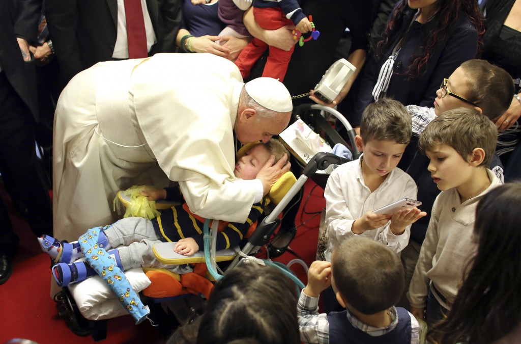 Pope Francis kisses a disabled child during a visit to the parish of Santa Maria dell'Orazione on the outskirts of Rome March 16. (CNS photo/Stefano Rellandini)