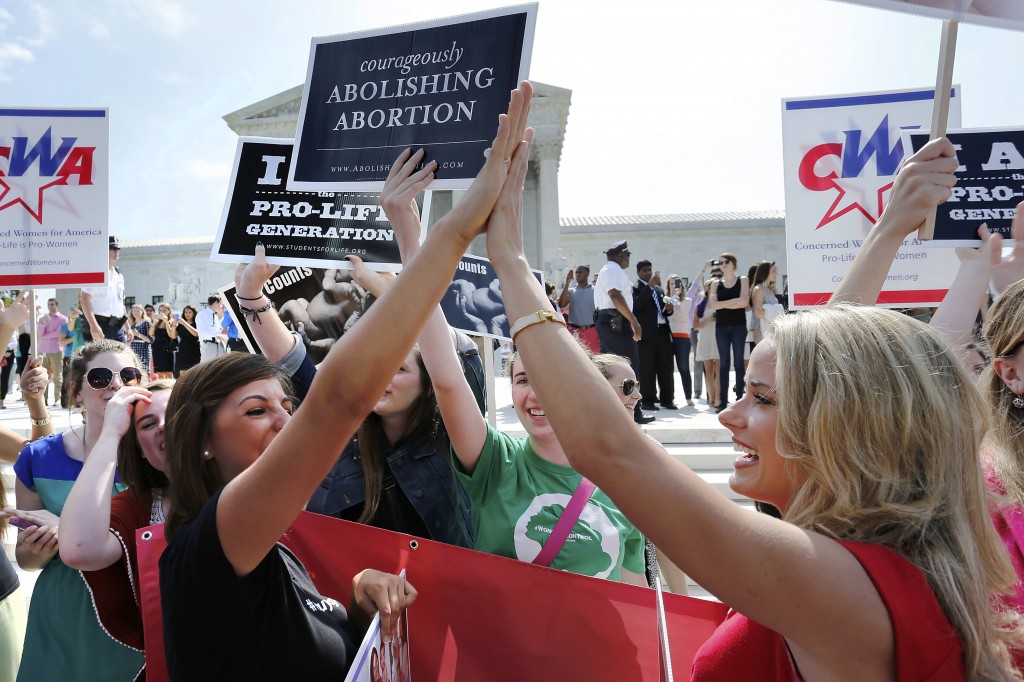 Pro-life demonstrators celebrate June 30 outside the U.S. Supreme Court in Washington as its decision in the Hobby Lobby case is announced. The high court ruled that owners of closely held corporations can object on religious grounds to being forced by the government to provide coverage of contraceptives for their employees. (CNS photo/ Jonathan Ernst) 
